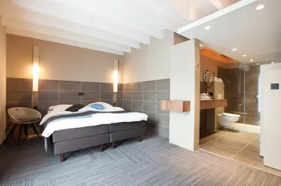 a bedroom with a bed and a bathroom at Hotel Vé in Mechelen