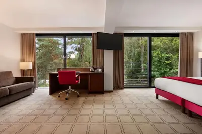 a hotel room with a bed and a desk with a computer at Hotel Dolce La Hulpe Brussels in La Hulpe