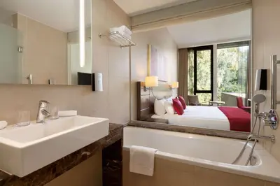 a bathroom with a sink and a bed and a mirror at Hotel Dolce La Hulpe Brussels in La Hulpe