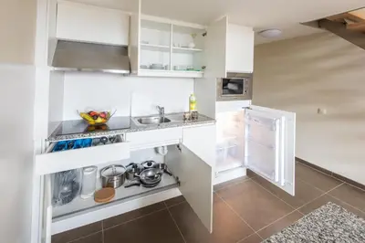 a kitchen with white cabinets and an open refrigerator at Arass Hôtel & Business Flats in Antwerp