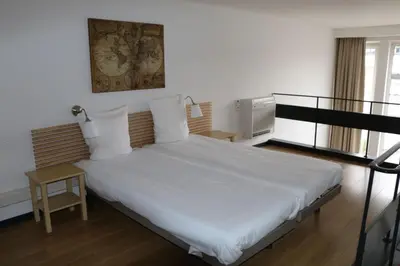a bedroom with a white bed and a balcony at Arass Hôtel & Business Flats in Antwerp