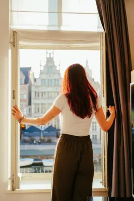 a woman is looking out of a window at Ghent Marriott Hotel in Ghent