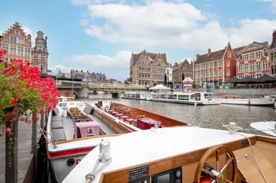 a group of boats docked in a river with buildings at Ghent Marriott Hotel in Ghent