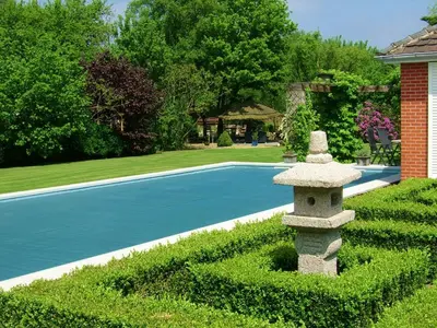 a stone birdbath in a garden next to a pool at Het Schalks Genot in Poppel