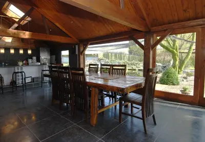 a kitchen and dining room with a wooden table and chairs at Het Schalks Genot in Poppel