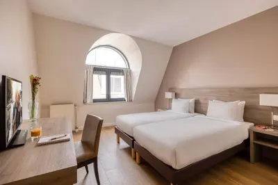 a hotel room with a bed and a desk at Citadines Toison d'Or Brussels in Brussels