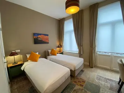 two beds in a hotel room with two windows at Hooome in Brussels