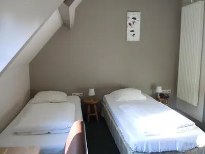 two beds in a room with a staircase at Hotel Malcot in Mechelen