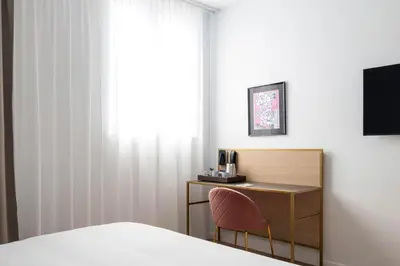 a bedroom with a desk and a bed and a window at Jill Hotel Brussels in Brussels