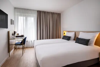 a hotel room with two beds and a desk at Jill Hotel Brussels in Brussels