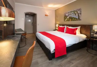 a hotel room with a large bed with red pillows at Martin's Brussels EU in Brussels