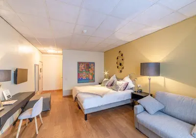 a bedroom with a bed and a desk and a couch at Hotel La Legende in Brussels