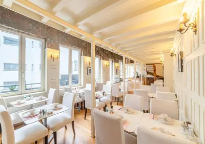 a restaurant with white tables and chairs and windows at Hotel La Legende in Brussels