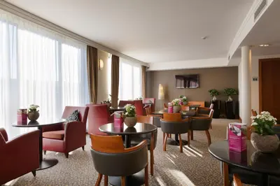 a hotel lobby with tables and chairs and a waiting room at Crowne Plaza Brussels Airport by IHG in Zaventem