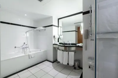 a white bathroom with a tub and a sink at Crowne Plaza Brussels Airport by IHG in Zaventem
