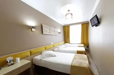 a hotel room with three beds and a television at Hotel de France in Brussels