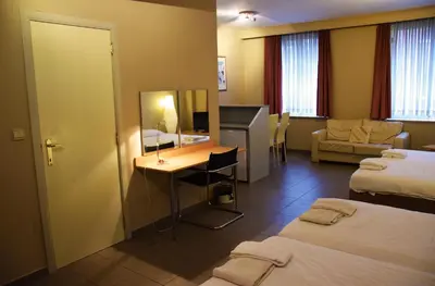 a hotel room with two beds and a desk at City Apartments Antwerpen in Antwerp