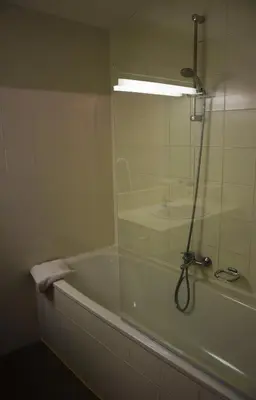 a bathroom with a bath tub with a glass shower door at City Apartments Antwerpen in Antwerp
