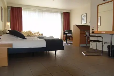 a bedroom with a bed and a desk and a window at City Apartments Antwerpen in Antwerp