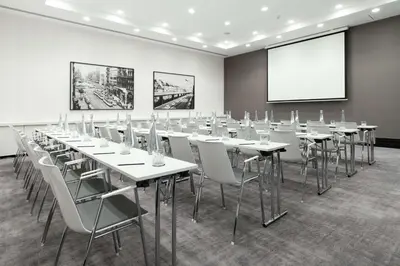 a conference room with white tables and chairs and a screen at Radisson Collection Grand Place Brussels in Brussels