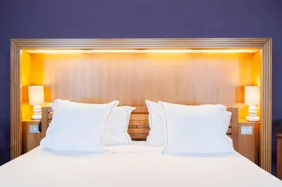 a large bed with white pillows and two lamps at Hotel Hof van Aragon in Lier