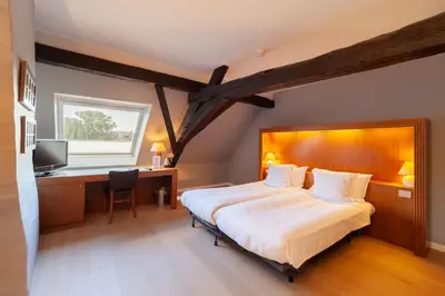 a bedroom with a bed and a desk and a television at Hotel Hof van Aragon in Lier