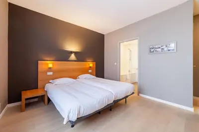 a bedroom with a large white bed with a wooden headboard at Hotel Hof van Aragon in Lier