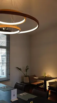 a restaurant with tables and chairs and a large light fixture at Hotel Hof van Aragon in Lier