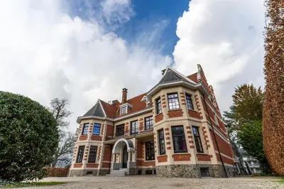a large brick house on a cloudy day at Hotel Villa Monte in Heist-op-den-Berg
