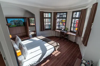 a bedroom with a bed and a desk and windows at Hotel Villa Monte in Heist-op-den-Berg