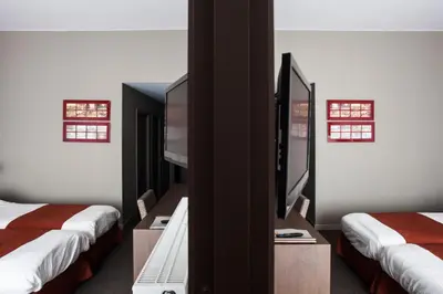 a room with two beds and a desk with a computer at Hotel Rastelli Tervuren in Tervuren