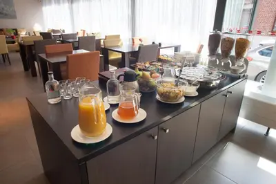 a breakfast buffet with glasses of orange juice and food at Hotel Rastelli Tervuren in Tervuren