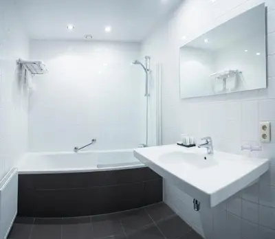 a white bathroom with a sink and a bath tub at Hotel Rastelli Tervuren in Tervuren