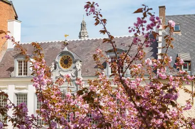 a building with a clock on it with pink flowers at Hotel Rubens-Grote Markt in Antwerp