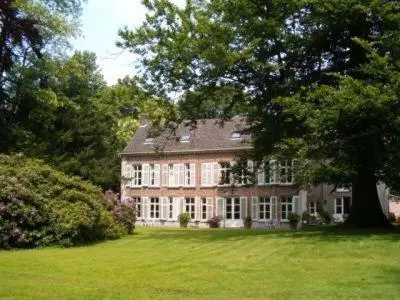 a large brick house with a tree in a field at Eremyten Hof in Evergem