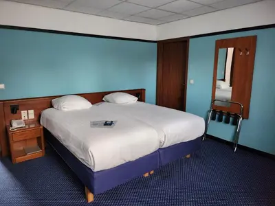 a bedroom with a large bed with a blue wall at Hotel Royal Zelzate in Zelzate