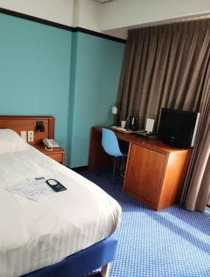 a hotel room with a bed and a desk with a computer at Hotel Royal Zelzate in Zelzate