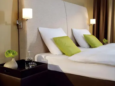 a hotel room with two beds with green pillows at Lindner Hotel Antwerp, part of JdV by Hyatt in Antwerp