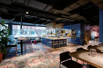 a large room with tables and chairs and a store at Lindner Hotel Antwerp, part of JdV by Hyatt in Antwerp