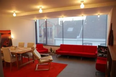 a living room with a table and a red couch at Aparthotel Malpertuus in Aalst