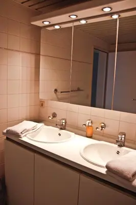 a bathroom with a sink and a large mirror at Ambassador Suites Antwerp in Antwerp