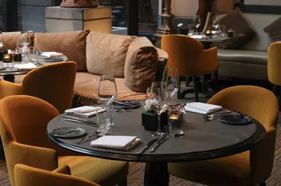 a table with glasses and a couch in a restaurant at The Dominican, Brussels, a Member of Design Hotels in Brussels