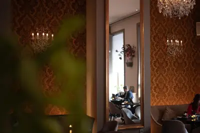 a mirror in a restaurant with people sitting at tables at The Dominican, Brussels, a Member of Design Hotels in Brussels
