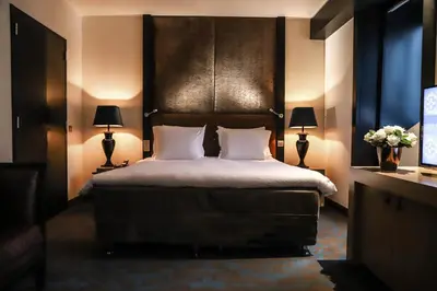 a bedroom with a bed and two lamps and a television at The Dominican, Brussels, a Member of Design Hotels in Brussels