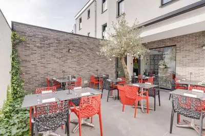 a patio with tables and chairs and a brick wall at Hotel Italia in Zelzate