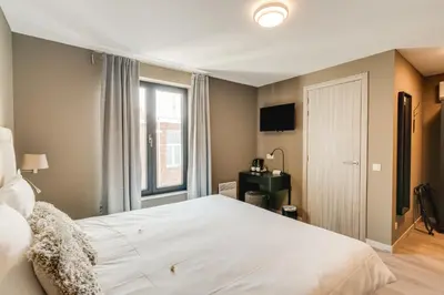 a bedroom with a large white bed and a window at Hotel Italia in Zelzate