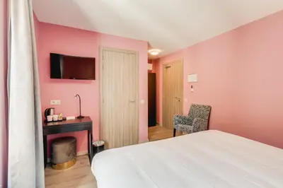 a bedroom with pink walls and a bed and a desk at Hotel Italia in Zelzate