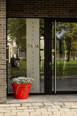 a sign in front of a door with a flower pot at Hotel Italia in Zelzate