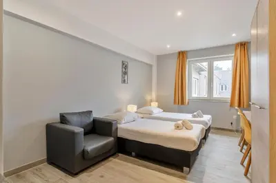 a bedroom with a bed and a chair at Budget Flats Leuven in Leuven