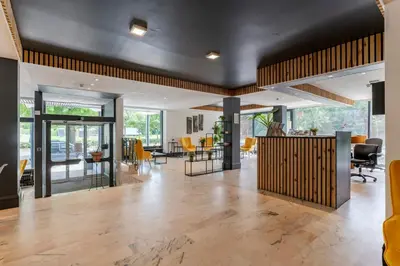 an open living room with a lobby with yellow chairs at Sleep & Go Brussels South in Waterloo